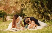 A happy family having a picnic in a lush green park setting during the day.